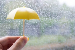 雨の日に小さい黄色の傘を持つ手